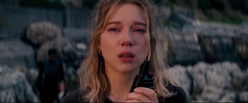 Movie still from “No Time to Die” (2021), directed by Cary Joji Fukunaga – A woman holding a cell phone up to her face; Close Up shot, High angle