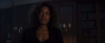 Movie still from “No Time to Die” (2021), directed by Cary Joji Fukunaga – A woman that is standing in the dark; Close Up shot, Over the shoulder angle