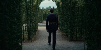 Movie still from “The Empress” (2022), created by Katharina Eyssen – A man in a uniform walking through a tunnel of trees; Wide shot, Over the shoulder angle