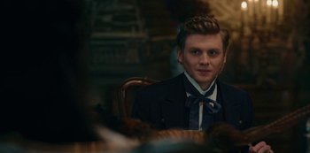 Movie still from “The Empress” (2022), created by Katharina Eyssen – A man sitting at a table wearing a suit and bow tie; Close Up shot, Over the shoulder angle
