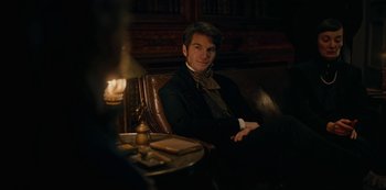 Movie still from “The Empress” (2022), created by Katharina Eyssen – A man sitting in a chair in front of candles; Medium shot, Over the shoulder angle