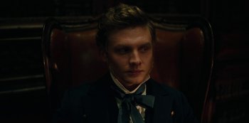 Movie still from “The Empress” (2022), created by Katharina Eyssen – A man in a suit and bow tie is sitting in a chair; Close Up shot, Low angle