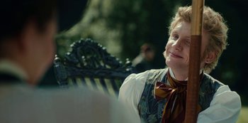 Movie still from “The Empress” (2022), created by Katharina Eyssen – A young man sitting on top of a wooden bench; Close Up shot, Over the shoulder angle