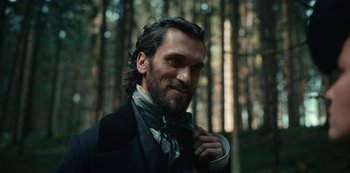 Movie still from “The Empress” (2022), created by Katharina Eyssen – A man with long hair wearing a suit and tie; Close Up shot, Over the shoulder angle