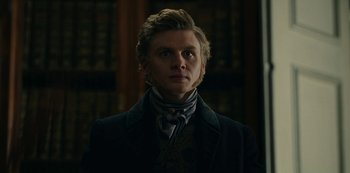 Movie still from “The Empress” (2022), created by Katharina Eyssen – A man in a suit standing in front of a bookshelf; Close Up shot, Low angle
