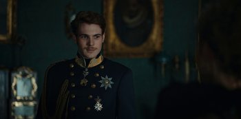 Movie still from “The Empress” (2022), created by Katharina Eyssen – A young man in a military uniform stands in front of a painting; Close Up shot, Over the shoulder angle
