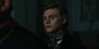 Movie still from “The Empress” (2022), created by Katharina Eyssen – A young man wearing a neck tie and a black jacket; Close Up shot, Over the shoulder angle