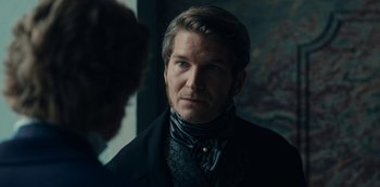 Movie still from “The Empress” (2022), created by Katharina Eyssen – A person wearing a suit and tie; Close Up shot, Over the shoulder angle