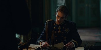 Movie still from “The Empress” (2022), created by Katharina Eyssen – A man in a military uniform is cutting paper; Medium shot, Over the shoulder angle