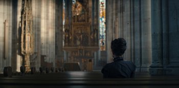 Movie still from “The Empress” (2022), created by Katharina Eyssen – A person sitting in front of an altar in a church; Extreme Wide shot, High angle