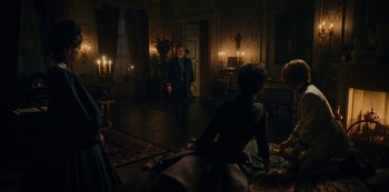Movie still from “The Empress” (2022), created by Katharina Eyssen – A group of people standing in a living room; Wide shot, Over the shoulder angle