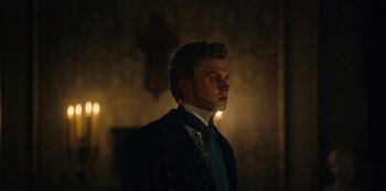 Movie still from “The Empress” (2022), created by Katharina Eyssen – A man wearing a suit and tie standing in front of a cross; Close Up shot, Low angle