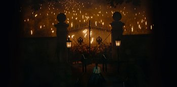 Movie still from “The Empress” (2022), created by Katharina Eyssen – People are standing in front of a gate with a bunch of flames coming out of it; Extreme Wide shot, High angle