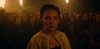 Movie still from “The Empress” (2022), created by Katharina Eyssen – A woman standing in front of a group of people; Close Up shot, Over the shoulder angle