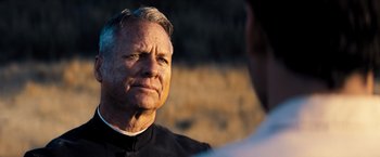 Movie still from “Babylon” (2022), directed by Damien Chazelle – An older man wearing a priest's outfit looking at a younger man; Close Up shot, Over the shoulder angle