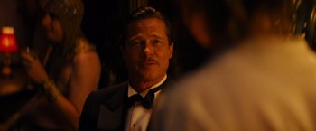 Movie still from “Babylon” (2022), directed by Damien Chazelle – A person wearing a suit and a bow tie; Close Up shot, Over the shoulder angle