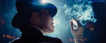 Movie still from “Babylon” (2022), directed by Damien Chazelle – A man smoking a cigarette while wearing a hat; Close Up shot, Low angle