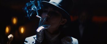 Movie still from “Babylon” (2022), directed by Damien Chazelle – A man in a hat and gloves smoking a cigarette; Close Up shot, Low angle