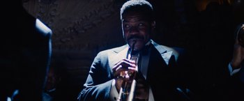 Movie still from “Babylon” (2022), directed by Damien Chazelle – A man in a suit and tie holding a trumpet; Close Up shot, Low angle