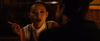 Movie still from “Babylon” (2022), directed by Damien Chazelle – A woman is talking to a man in a dark room; Close Up shot, Over the shoulder angle