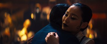 Movie still from “Babylon” (2022), directed by Damien Chazelle – A woman hugging another woman in a dark room; Close Up shot, Over the shoulder angle