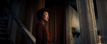 Movie still from “Babylon” (2022), directed by Damien Chazelle – A woman standing in front of a curtain; Medium shot, Low angle