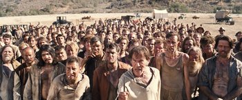 Movie still from “Babylon” (2022), directed by Damien Chazelle – A large group of people standing in the dirt; Wide shot, High angle
