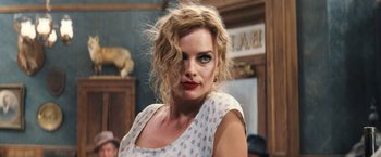 Movie still from “Babylon” (2022), directed by Damien Chazelle – A beautiful woman with blonde curly hair wearing a white top; Close Up shot, Over the shoulder angle