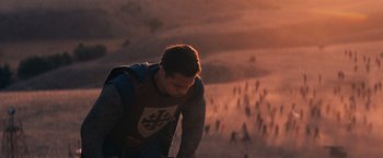 Movie still from “Babylon” (2022), directed by Damien Chazelle – A man standing in a field with a bunch of people in the background; Extreme Wide shot, High angle