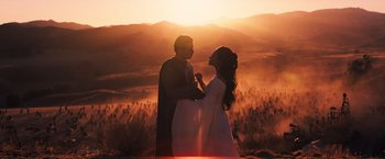 Movie still from “Babylon” (2022), directed by Damien Chazelle – A man and a woman standing next to each other in a field; Wide shot, Low angle