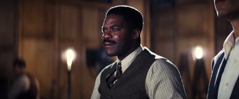 Movie still from “Babylon” (2022), directed by Damien Chazelle – A man in a vest and tie looking to his left; Close Up shot, Low angle