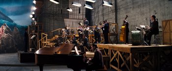Movie still from “Babylon” (2022), directed by Damien Chazelle – A group of men in suits playing instruments on a stage; Extreme Wide shot, High angle