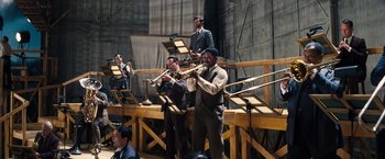Movie still from “Babylon” (2022), directed by Damien Chazelle – A group of men playing musical instruments on a stage; Wide shot, Low angle