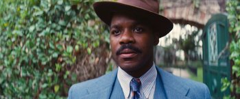 Movie still from “Babylon” (2022), directed by Damien Chazelle – A man wearing a suit and a brown hat; Close Up shot, Low angle
