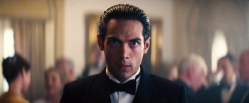 Movie still from “Babylon” (2022), directed by Damien Chazelle – A person wearing a suit and bow tie; Close Up shot, Low angle