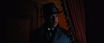 Movie still from “Babylon” (2022), directed by Damien Chazelle – A man wearing a hat and a suit and tie; Medium shot, Low angle