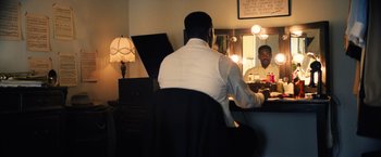Movie still from “Babylon” (2022), directed by Damien Chazelle – A man sitting in front of a mirror playing a piano; Medium shot, Over the shoulder angle