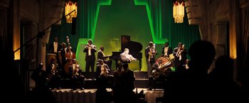 Movie still from “Babylon” (2022), directed by Damien Chazelle – A group of people on a stage with instruments; Extreme Wide shot, High angle