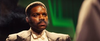 Movie still from “Babylon” (2022), directed by Damien Chazelle – A person wearing a suit and tie; Close Up shot, Low angle