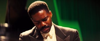 Movie still from “Babylon” (2022), directed by Damien Chazelle – A man in a white shirt and a suit; Close Up shot, Low angle