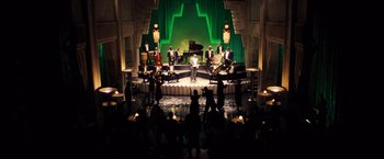 Movie still from “Babylon” (2022), directed by Damien Chazelle – A group of people on a stage with musical instruments; Extreme Wide shot, High angle