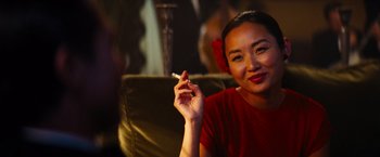 Movie still from “Babylon” (2022), directed by Damien Chazelle – A woman sitting in a chair holding a cigarette in her right hand; Close Up shot, Over the shoulder angle