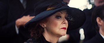 Movie still from “Babylon” (2022), directed by Damien Chazelle – An older woman wearing a black hat and red lipstick; Close Up shot, Over the shoulder angle