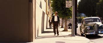 Movie still from “Babylon” (2022), directed by Damien Chazelle – A man walking down the street with a woman; Wide shot, Low angle