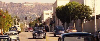 Movie still from “Babylon” (2022), directed by Damien Chazelle – A street scene with cars driving down the road; Extreme Wide shot, High angle