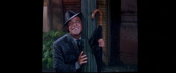 Movie still from “Babylon” (2022), directed by Damien Chazelle – A man in a suit and hat holding an umbrella; Medium shot, Low angle