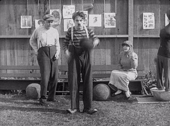 Movie still from “Babylon” (2022), directed by Damien Chazelle – A group of men and women sitting on a bench; Wide shot, Low angle
