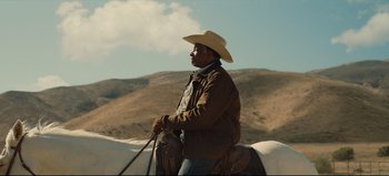 Movie still from “Nope” (2022), directed by Jordan Peele – A man in a cowboy hat riding on a horse; Medium shot, Low angle