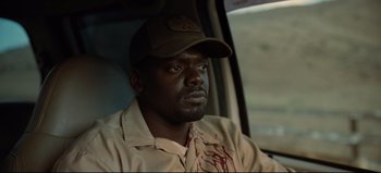 Movie still from “Nope” (2022), directed by Jordan Peele – A man in a baseball cap sitting in the back of a car; Close Up shot, Over the shoulder angle