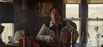 Movie still from “Nope” (2022), directed by Jordan Peele – A man sitting at a table in front of a lamp; Medium shot, Over the shoulder angle